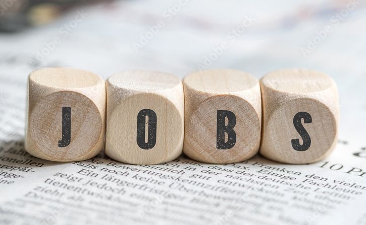 Holzblöcke mit den Buchstaben „J“, „O“, „B“ und „S“ stehen auf einer Zeitungsseite. Die Buchstaben bilden das Wort „JOBS“ und symbolisieren Arbeitsmöglichkeiten oder Stellenangebote.